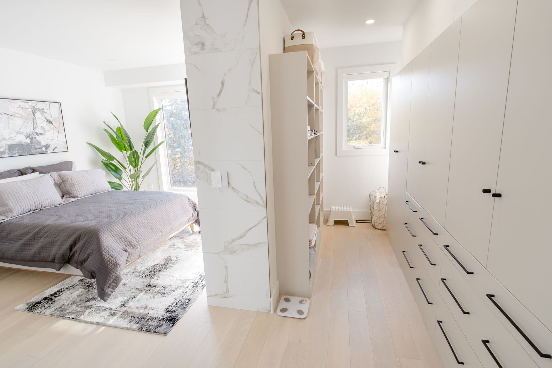 Bright and modern bedroom featuring a minimalist design with a walk-in closet and natural light.
