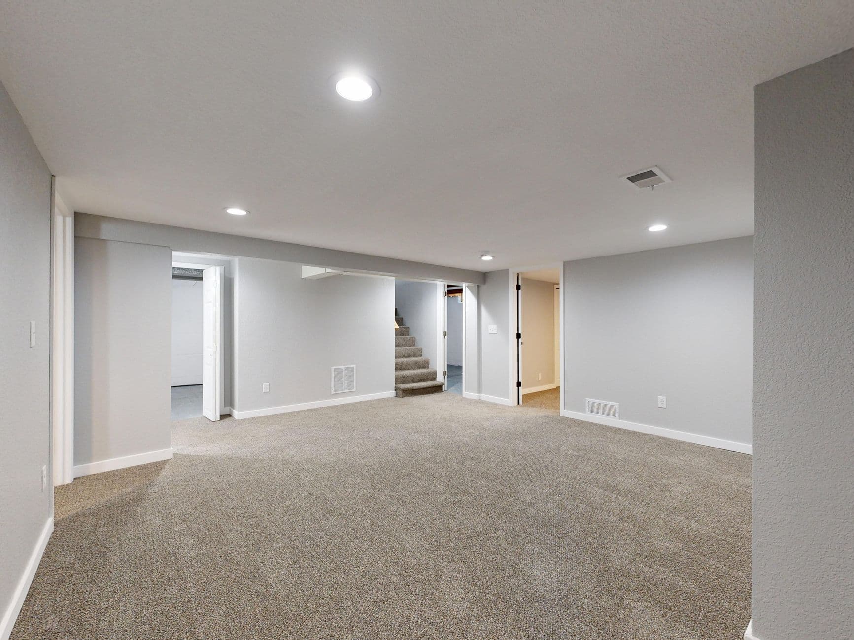Spacious modern basement with neutral design and carpet flooring, perfect for renovation or real estate listings.