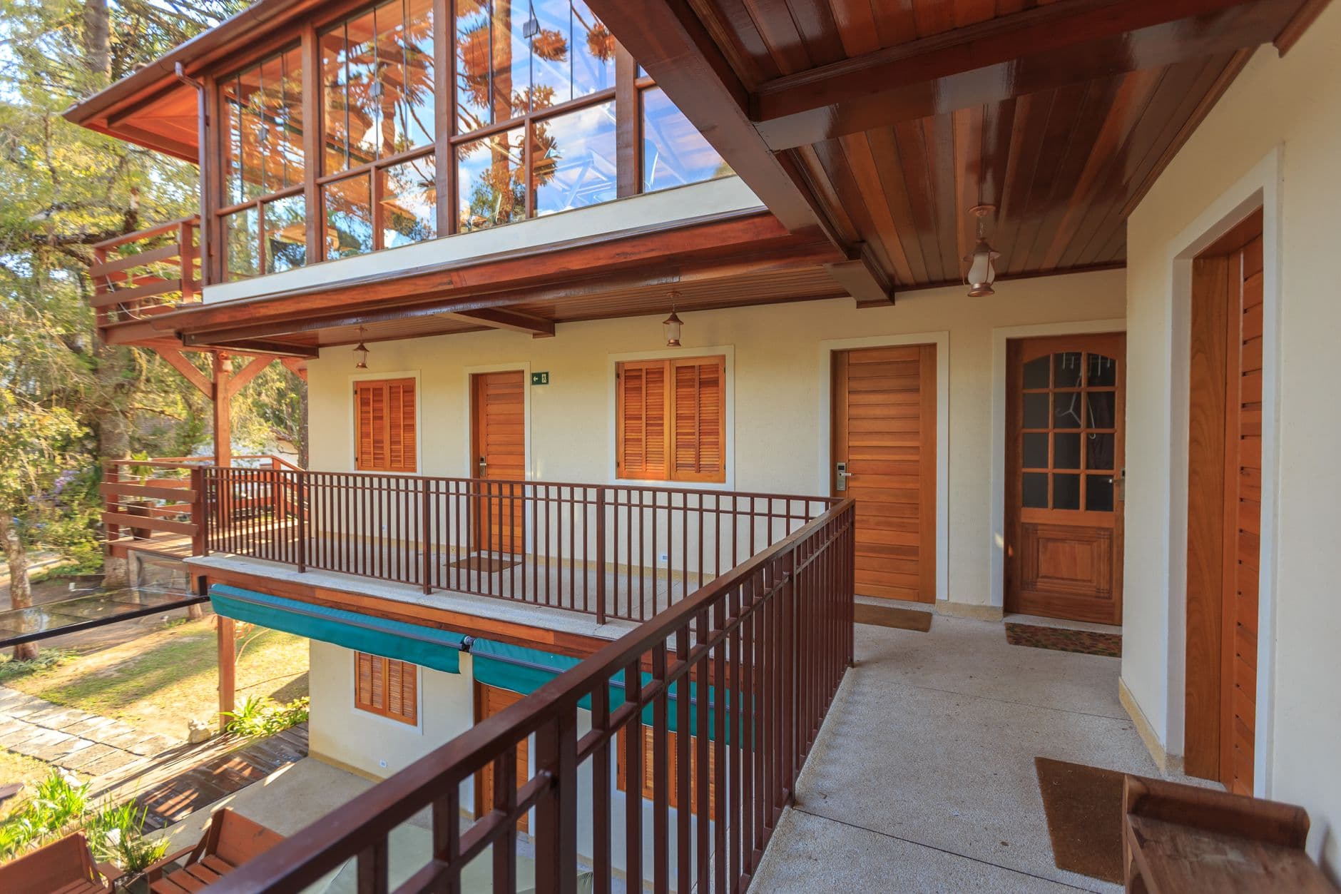 Charming villa exterior with wooden balcony and large windows showcasing natural views.