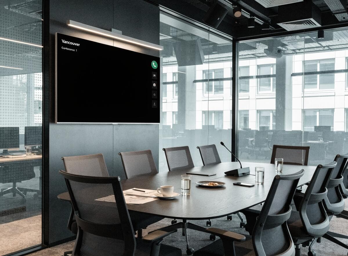 Modern corporate boardroom in Vancouver with wall-mounted videoconference screen and acoustic glass walls