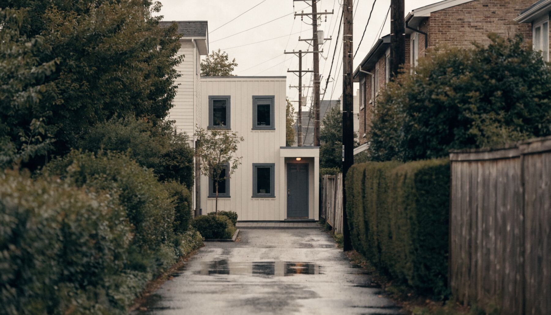 Completed two-storey laneway house facing a wet Vancouver back lane on an overcast afternoon