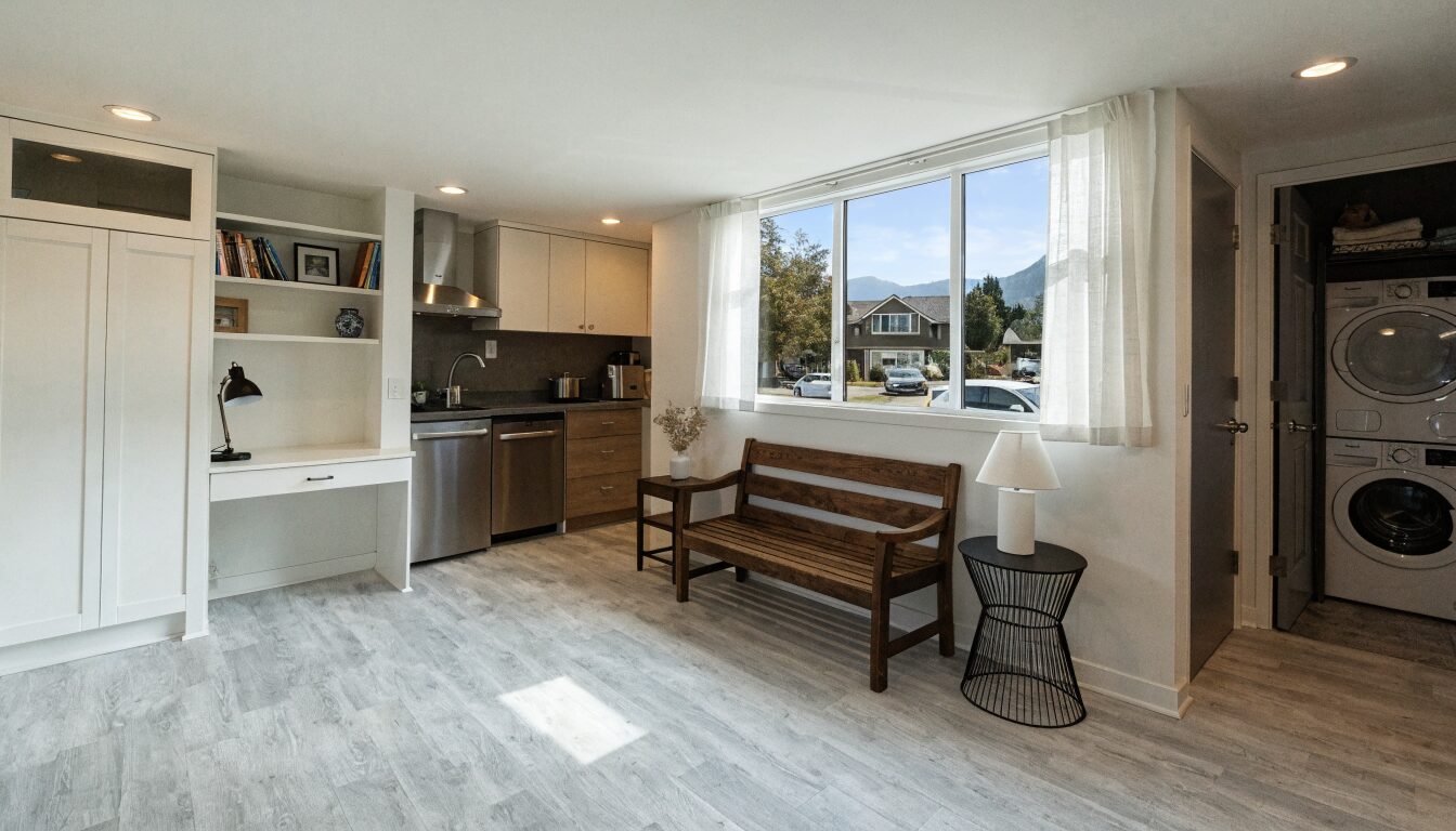 Legal basement suite in a North Vancouver hillside home: separate entry at grade, open living area, and egress windows.
