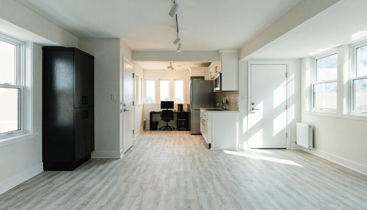 Bright legal basement suite interior with above-grade egress windows, compact white kitchen, and LVP flooring
