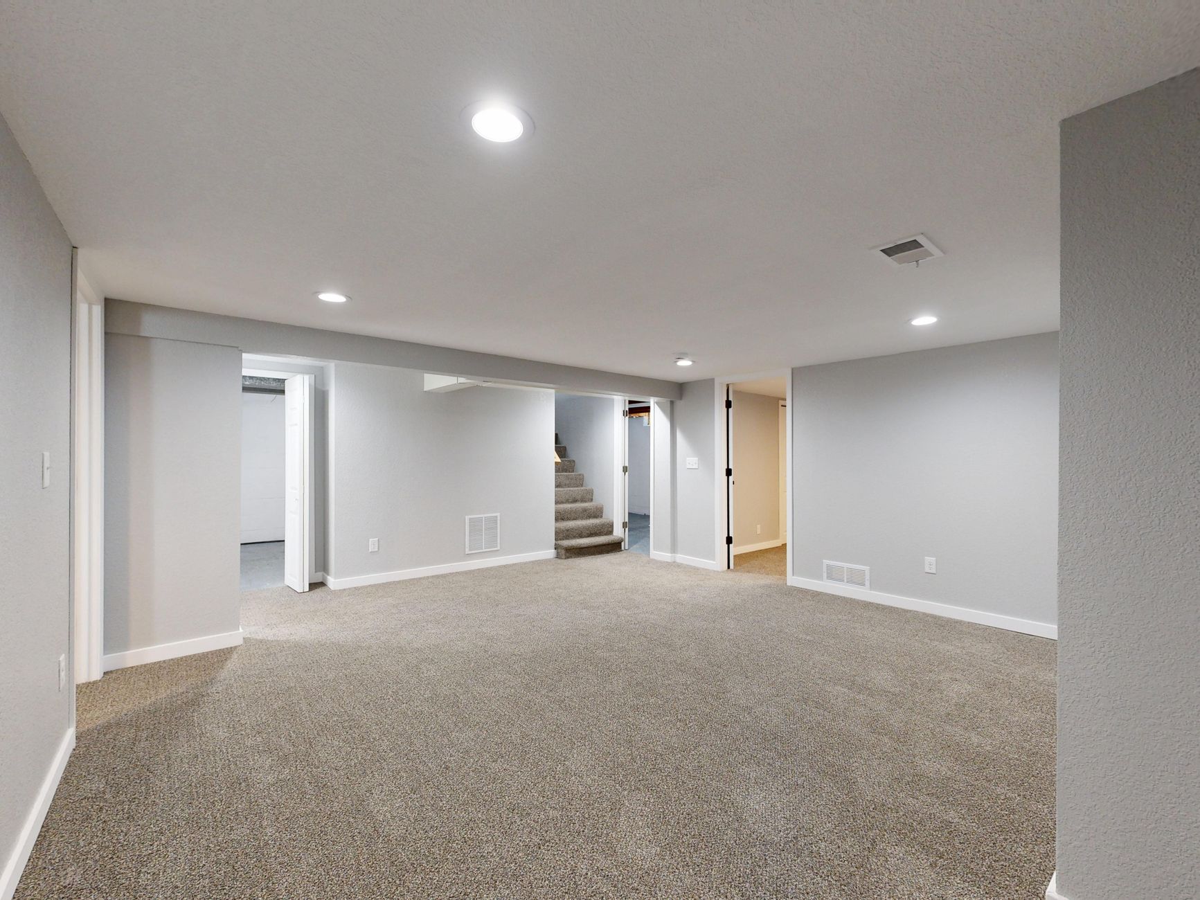 Spacious modern basement with neutral design and carpet flooring, perfect for renovation or real estate listings.