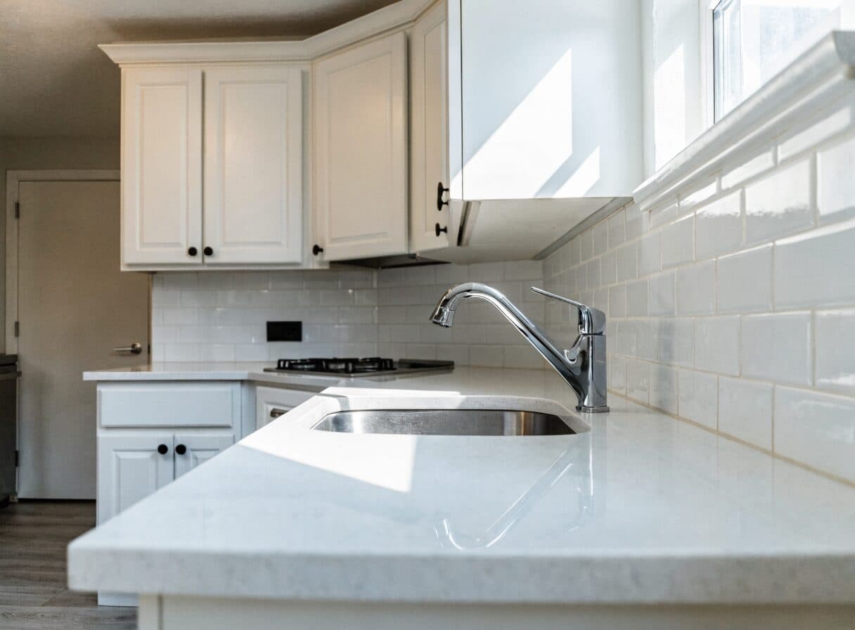 Completed Vancouver rental apartment kitchen refresh with new Shaker cabinet doors, quartz countertop, and subway tile backsplash