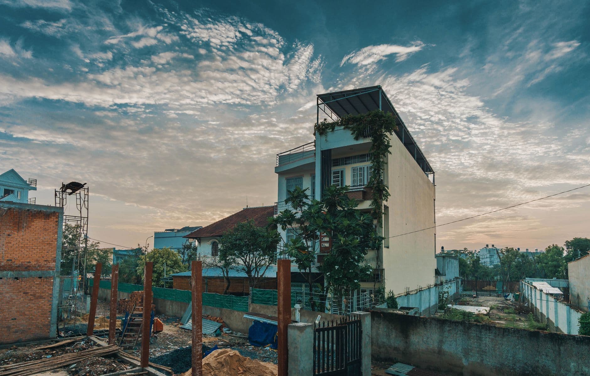 A building construction site in an urban area with a sunset sky backdrop.