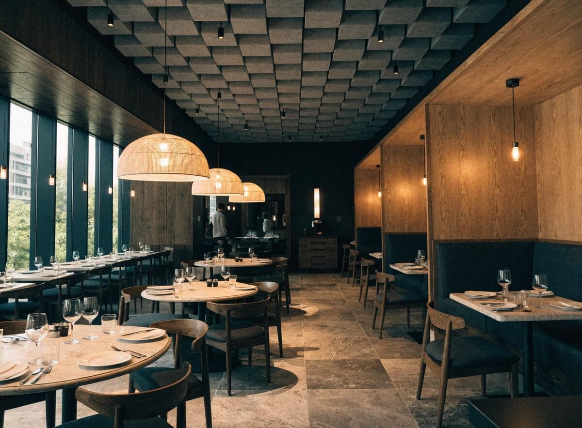 Completed restaurant dining room in Vancouver with acoustic ceiling panels and warm pendant lighting